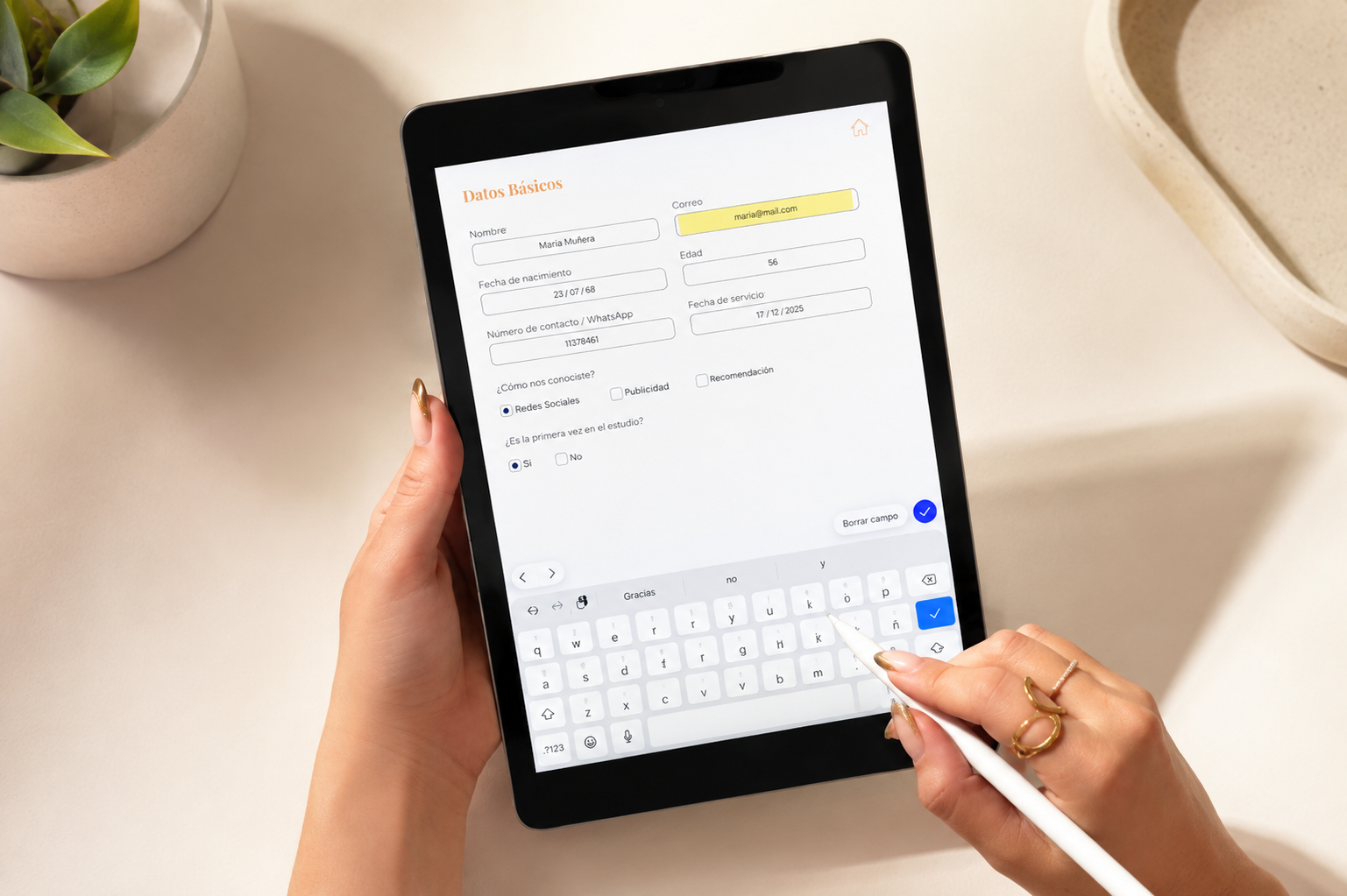 Ficha digital abierta en tablet, manos completándola